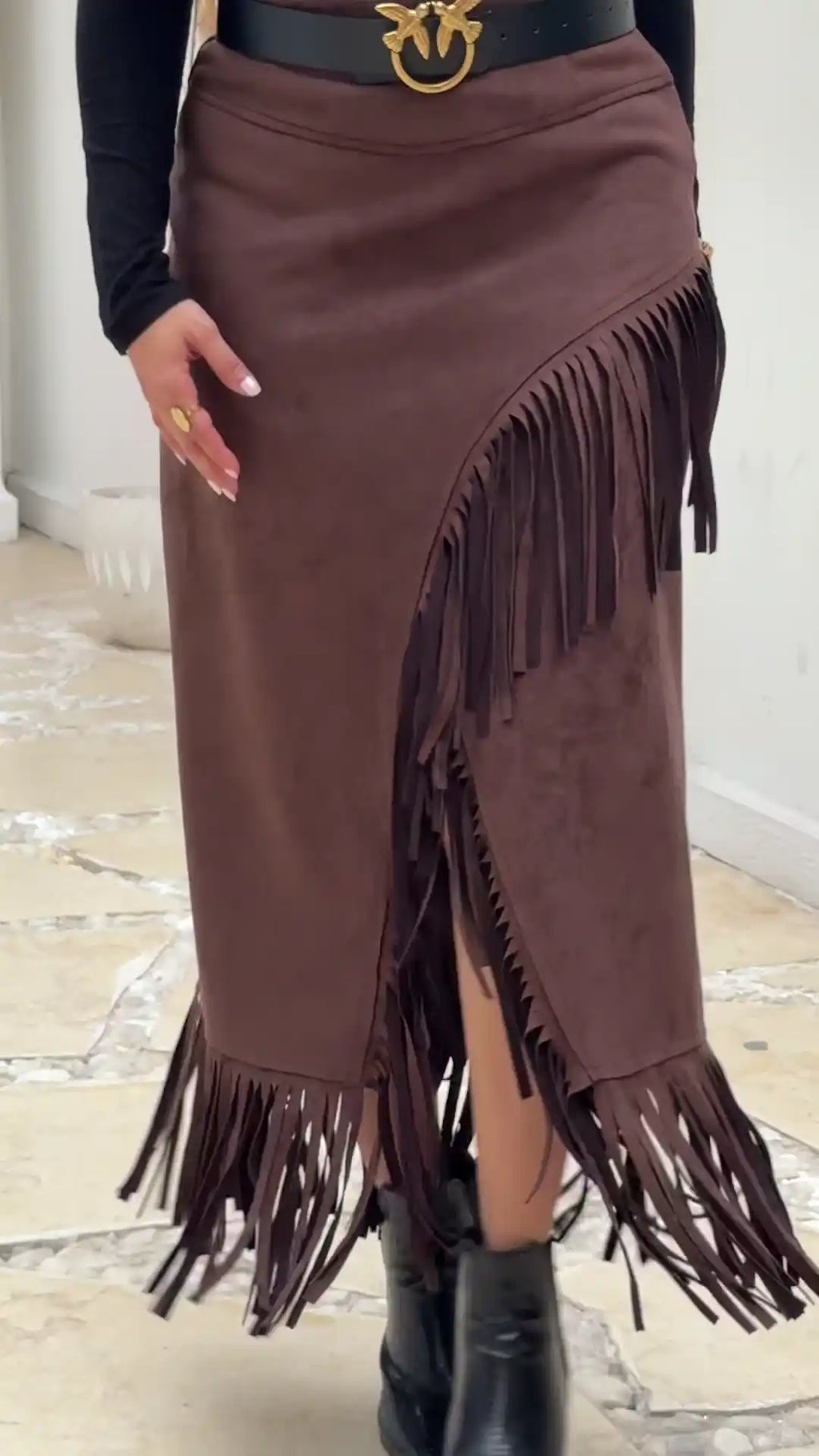 Brown fringed skirt with a belt and black boots on a light background