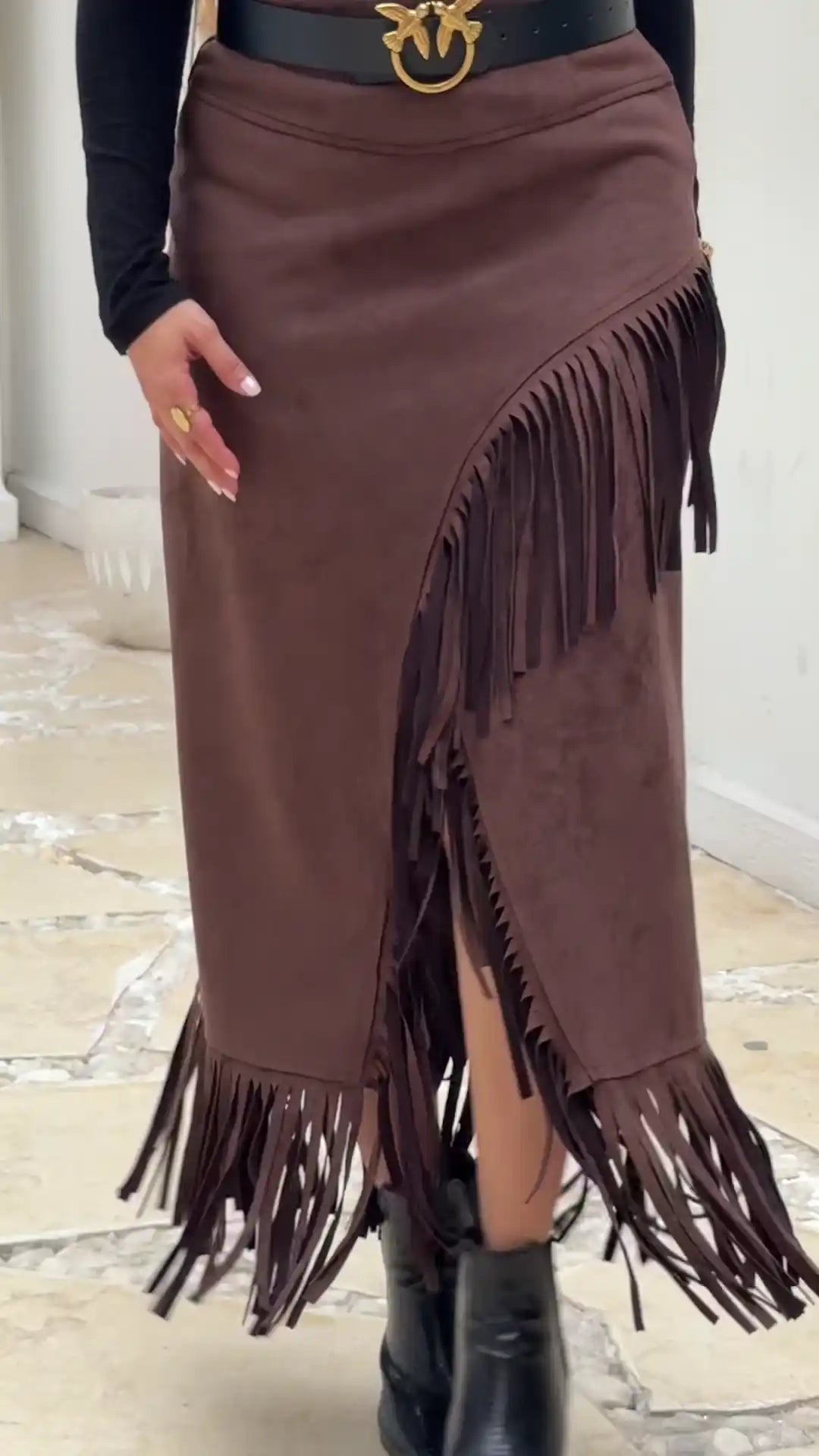 Brown fringed skirt with a belt and black boots on a light background